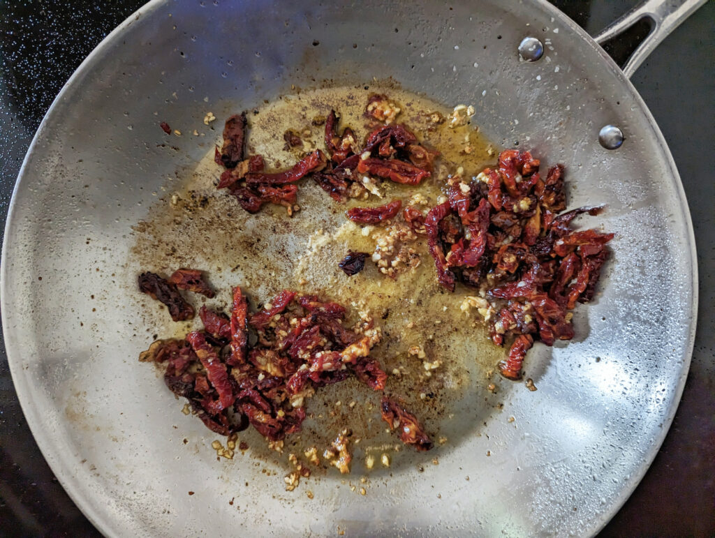 Sundried tomatoes, garlic, and tomato paste added to the skillet.