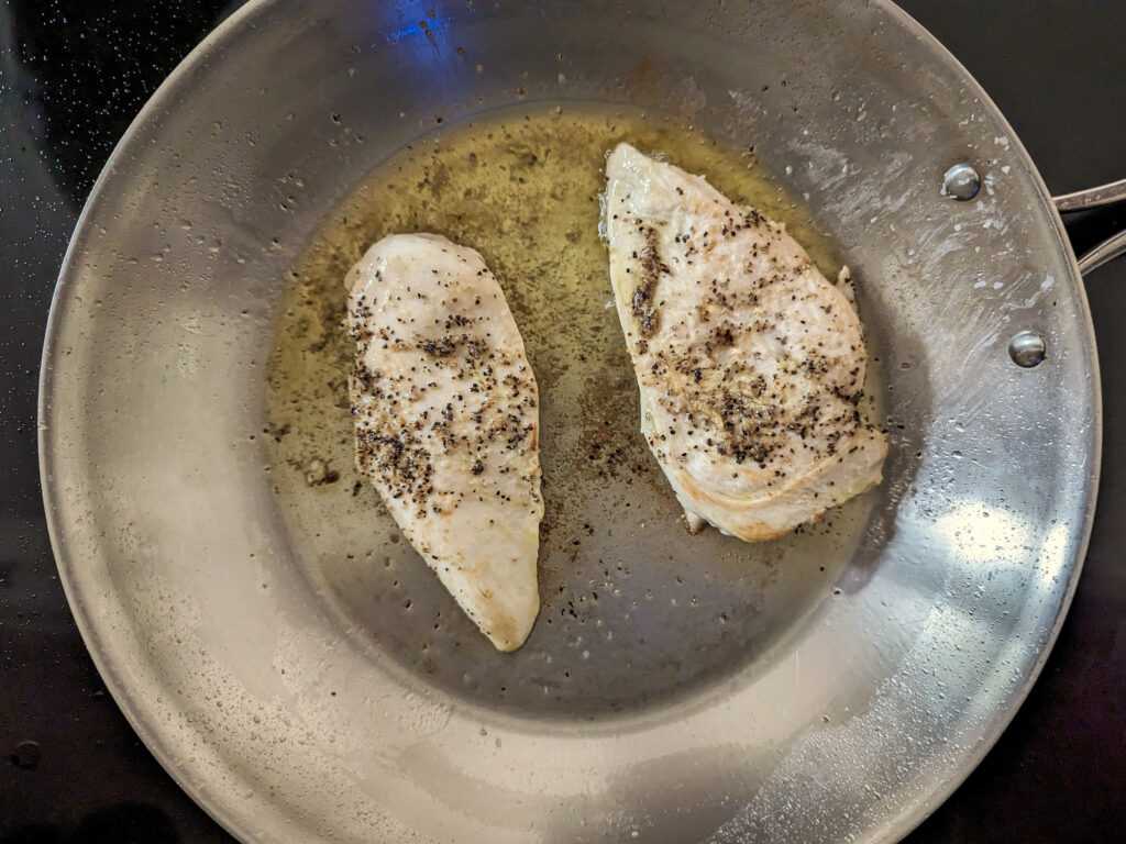 Chicken breasts searing in the pan.