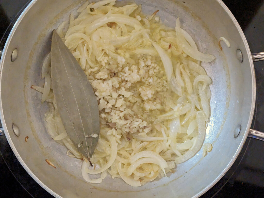 Ginger, garlic, and a bay leaf added to onion.