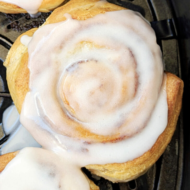 Cinnamon rolls in the air fryer with frosting on them.