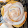 A cinnamon roll in the air fryer with frosting.