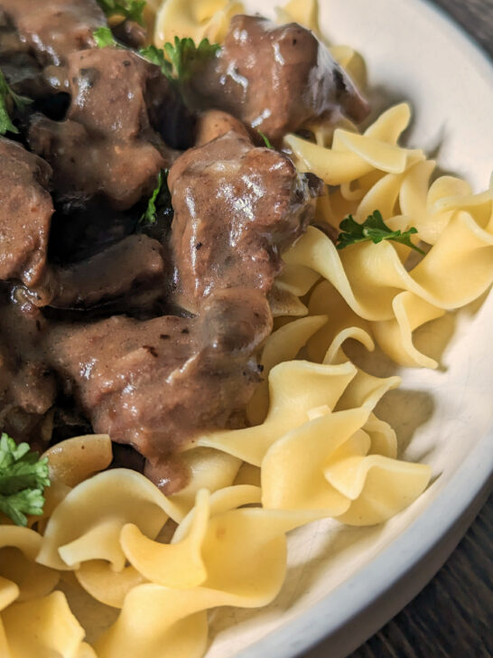 Buttered noodles topped with easy beef stroganoff and garnished with fresh parsley and sour cream.
