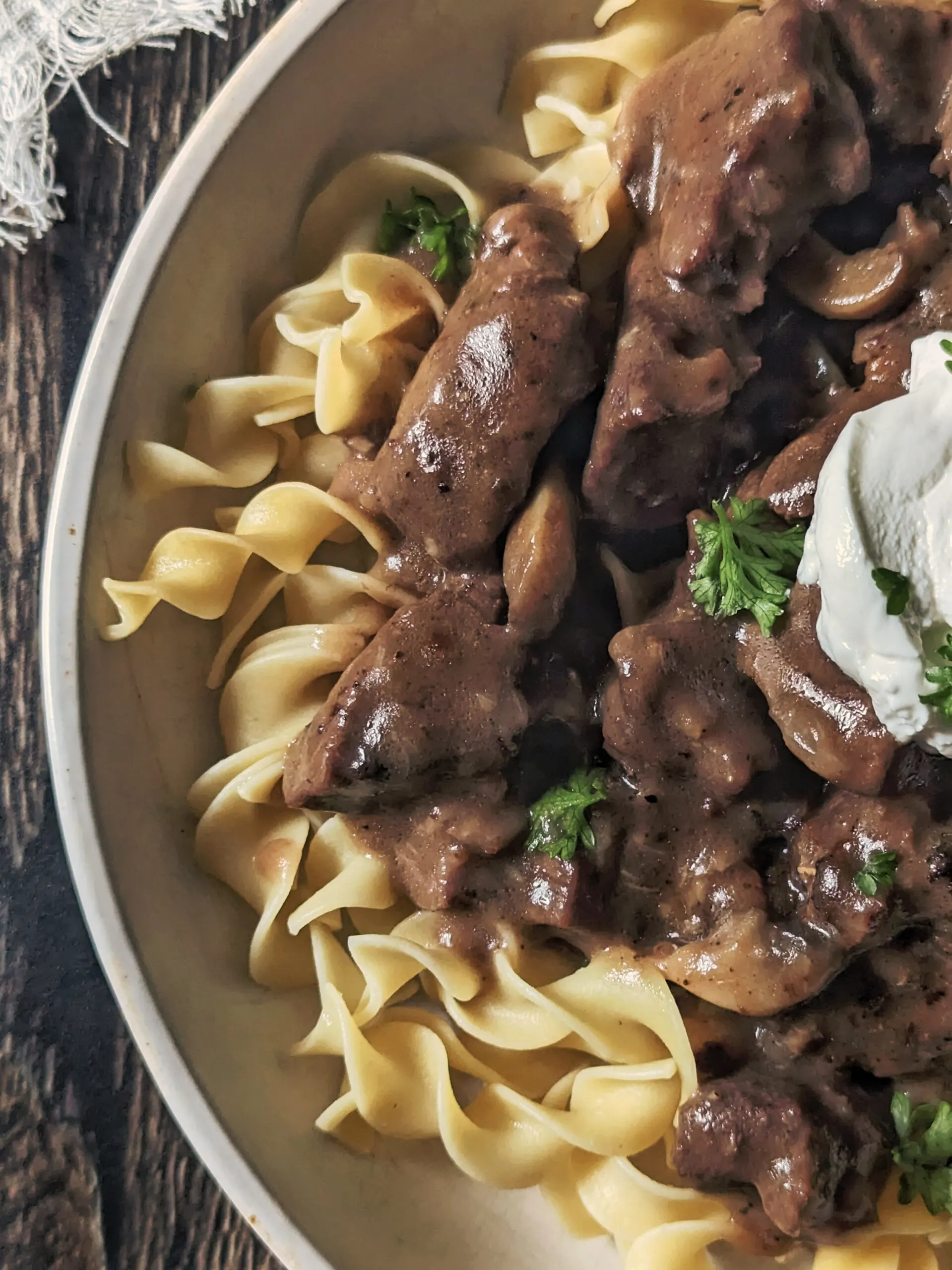Buttered noodles topped with easy beef stroganoff and garnished with fresh parsley and sour cream.