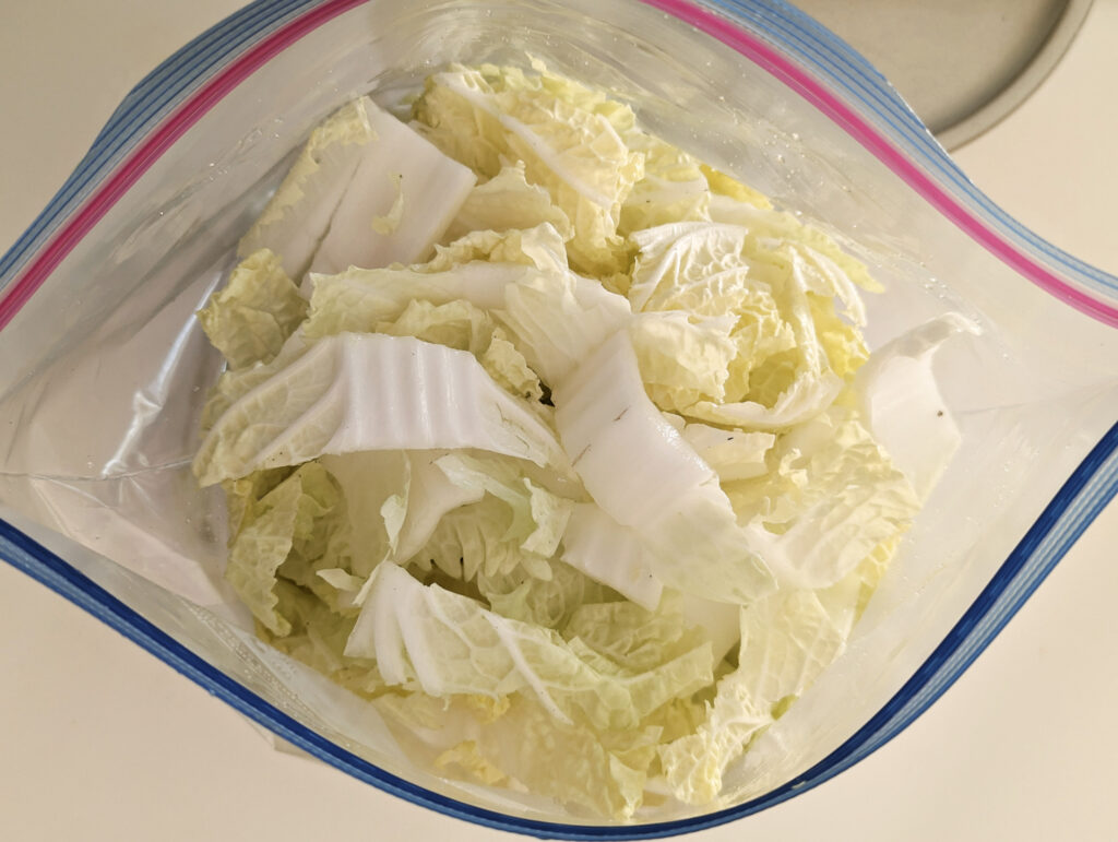 Chopped cabbage added to plastic bag.