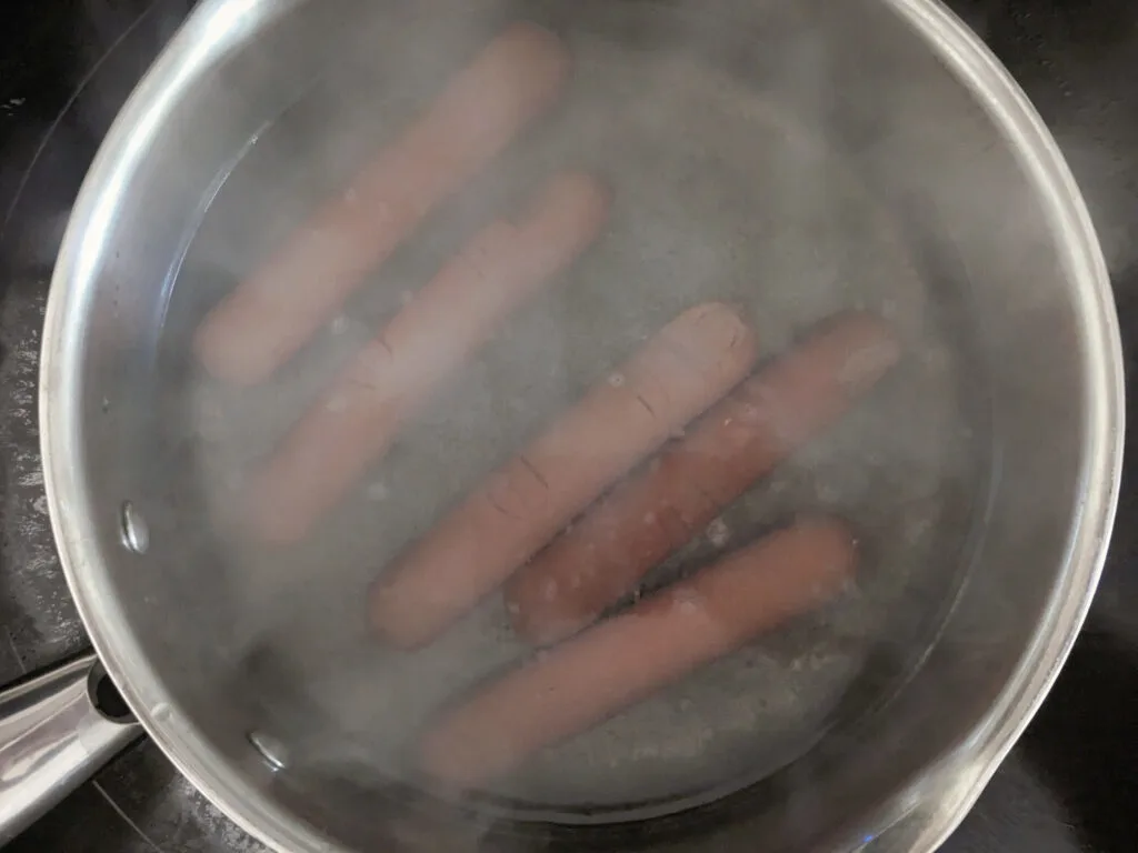 Hotdogs boiling in a saucepan.