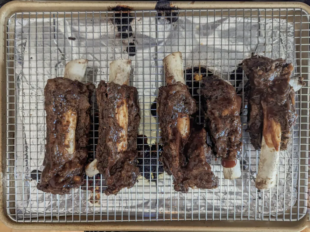 Ribs lined onto a wire rack in a rimmed baking sheet.