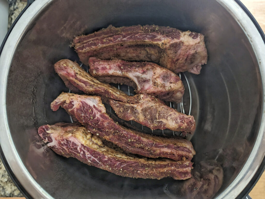 Individual ribs lined onto a trivet inside of the instant pot.