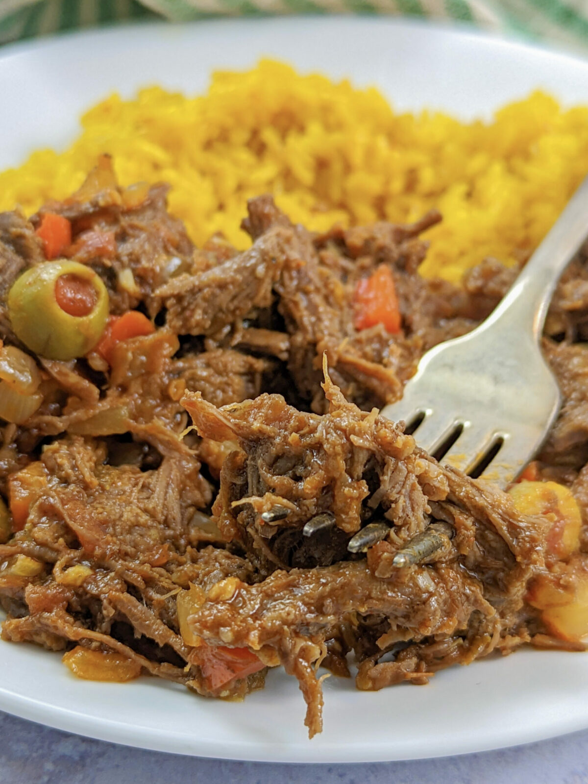 Instant pot ropa vieja on a plate with yellow rice.