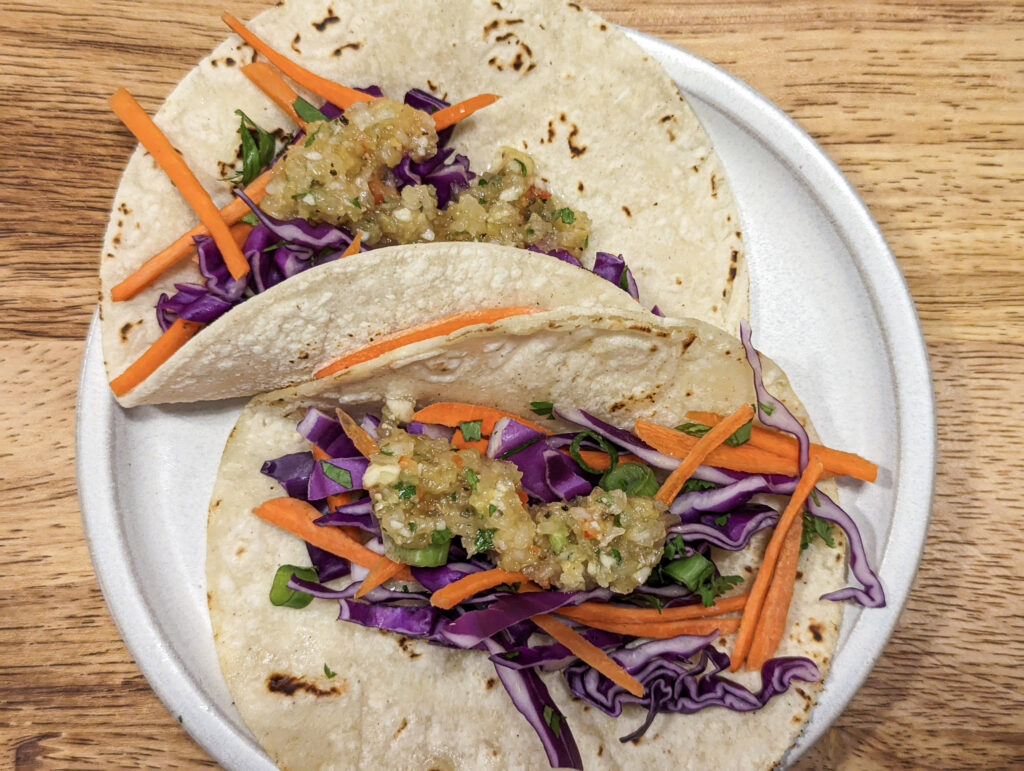 Corn tortillas topped with slaw and Caribbean hot sauce.