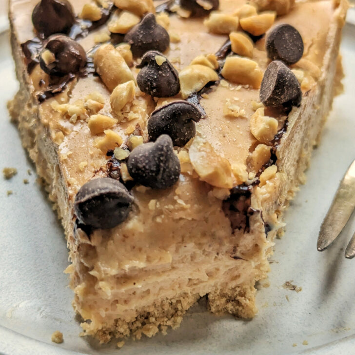 A slice of our Silky Peanut Butter Pie Recipe topped with chocolate syrup, melted peanut butter, chocolate chips, and peanuts.