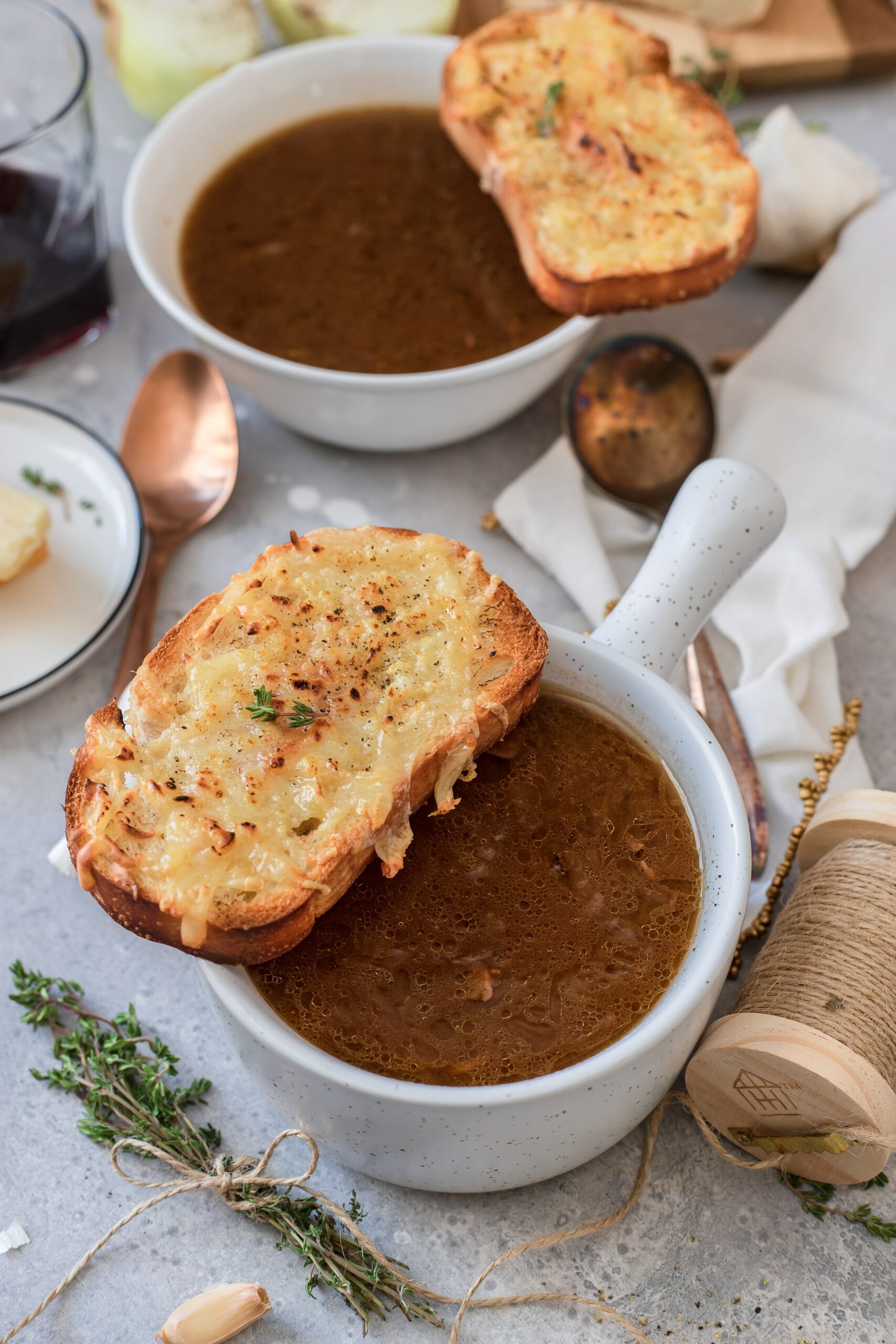 Two bowls of french onion soup topped with cheesy crusted bread. 