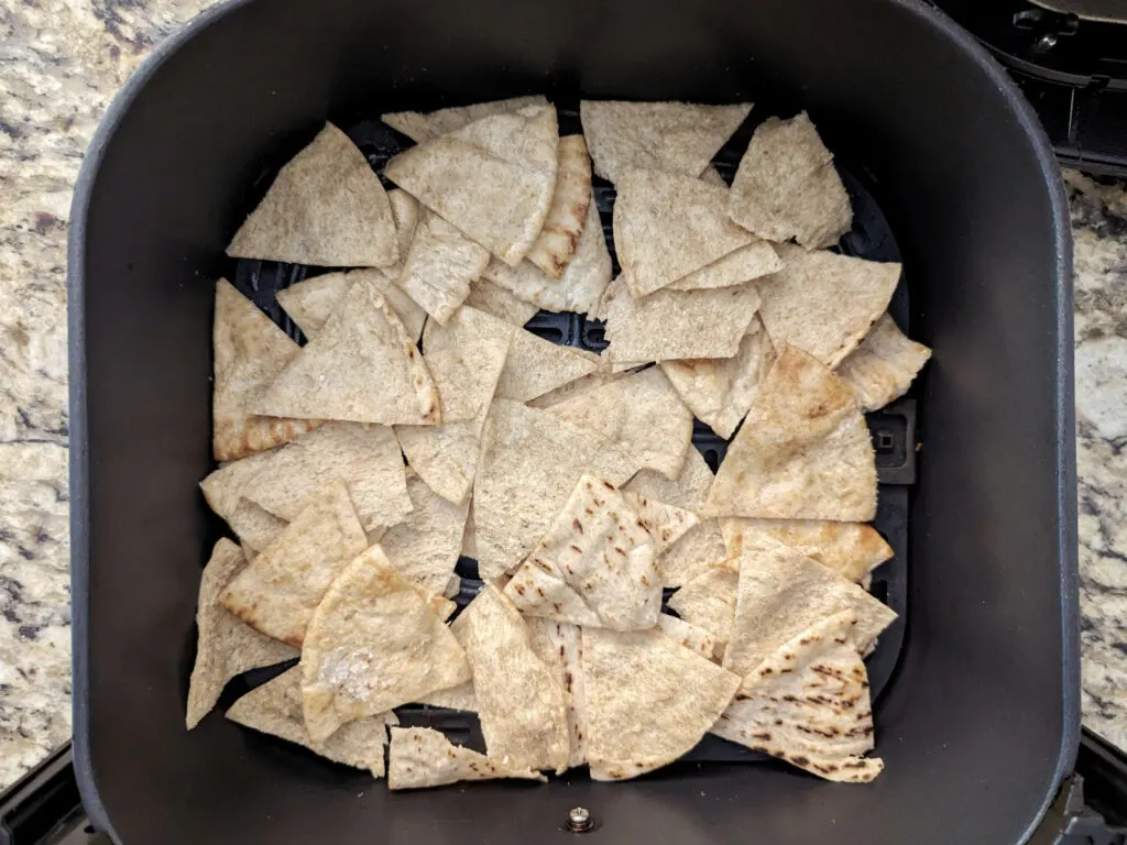 Pita chips layered into the air fryer basket.