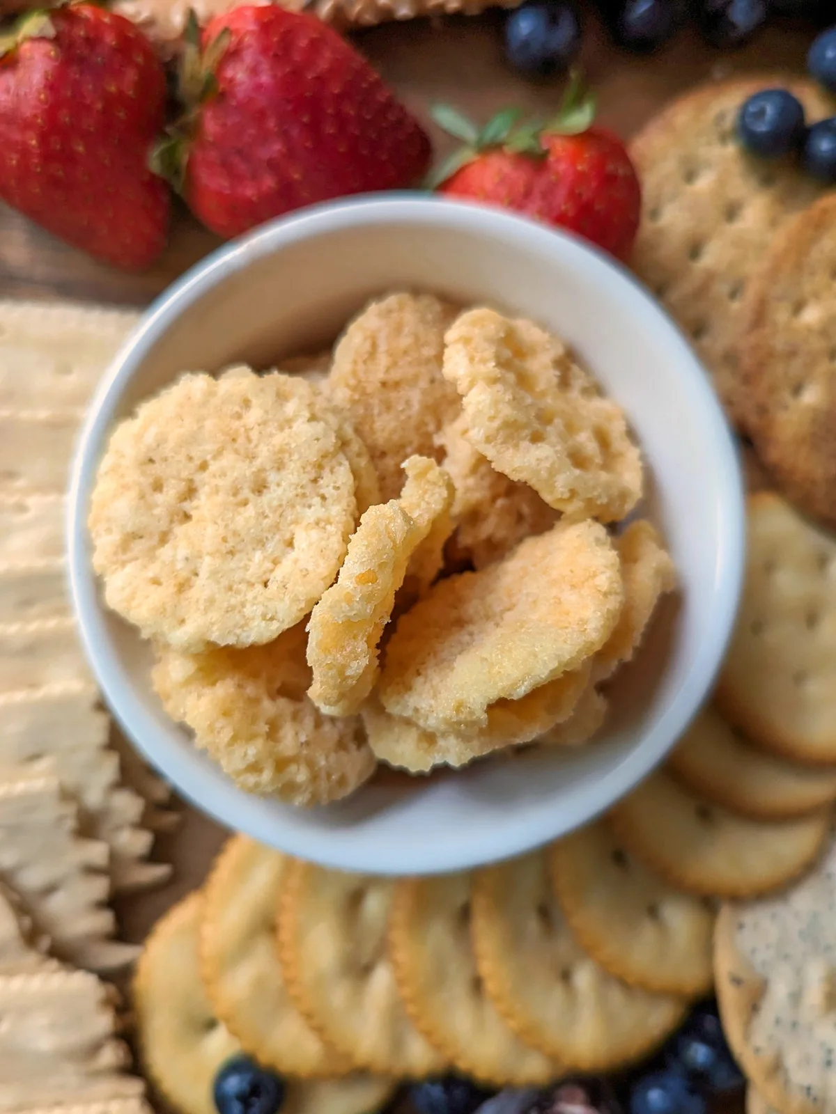 Cheese crackers in a bowl on a charcuterie board.