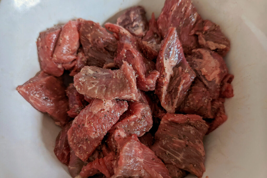 Cut and trimmed beef chuck in a mixing bowl.