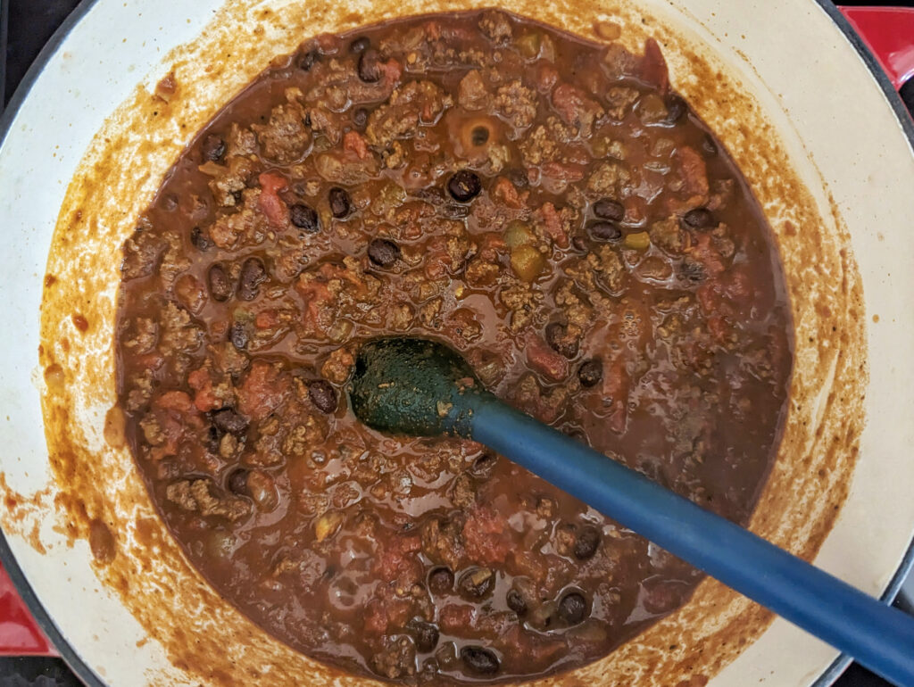 The chili cooking in a Dutch oven.