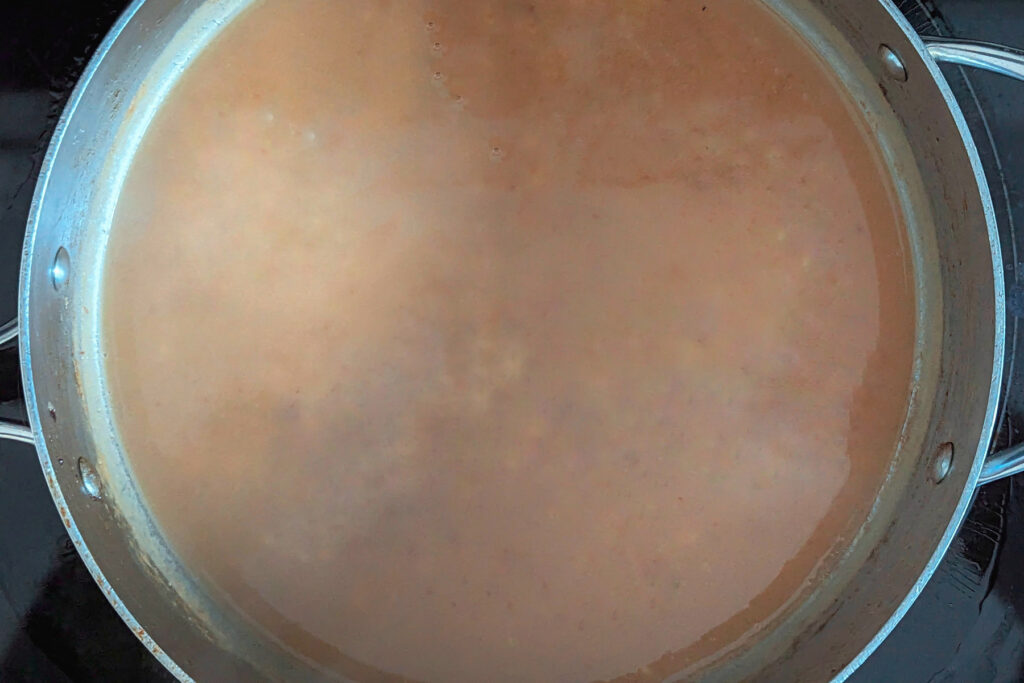 Broth added to the roux in a pan.
