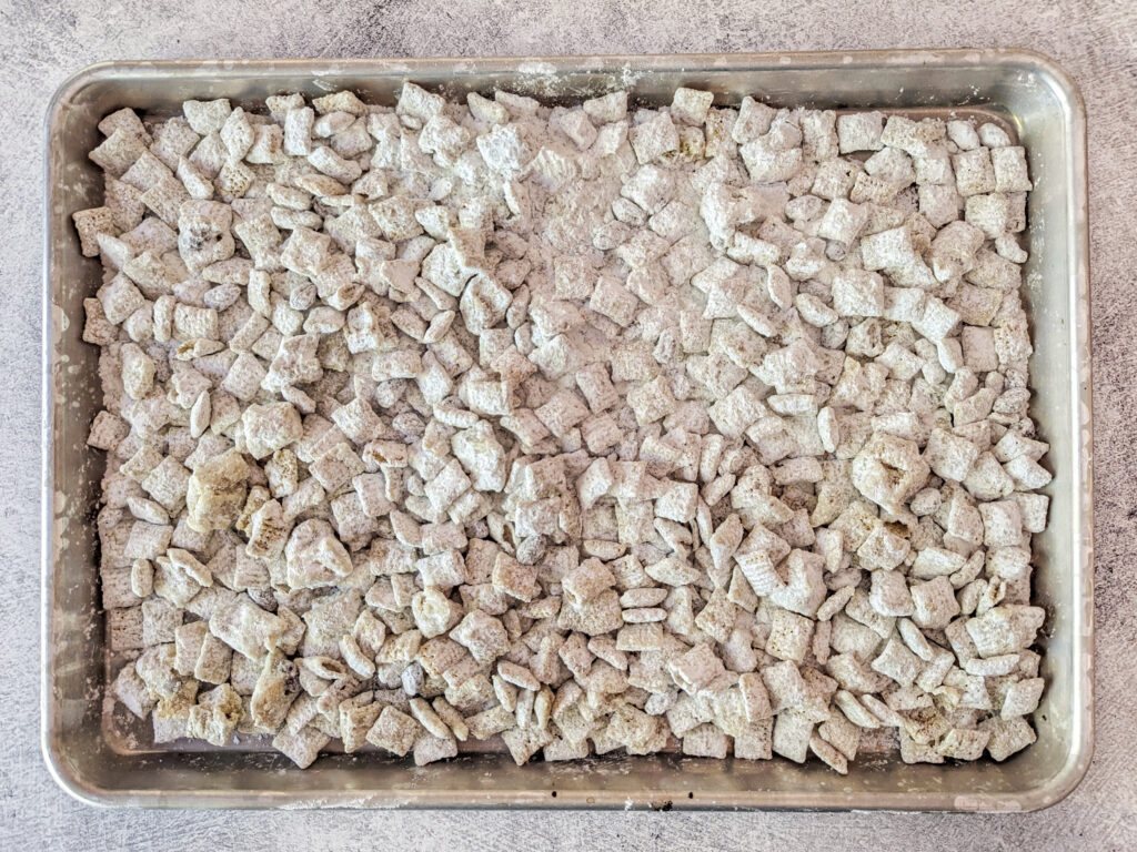 Spreading puppy chow onto a baking sheet to cool.