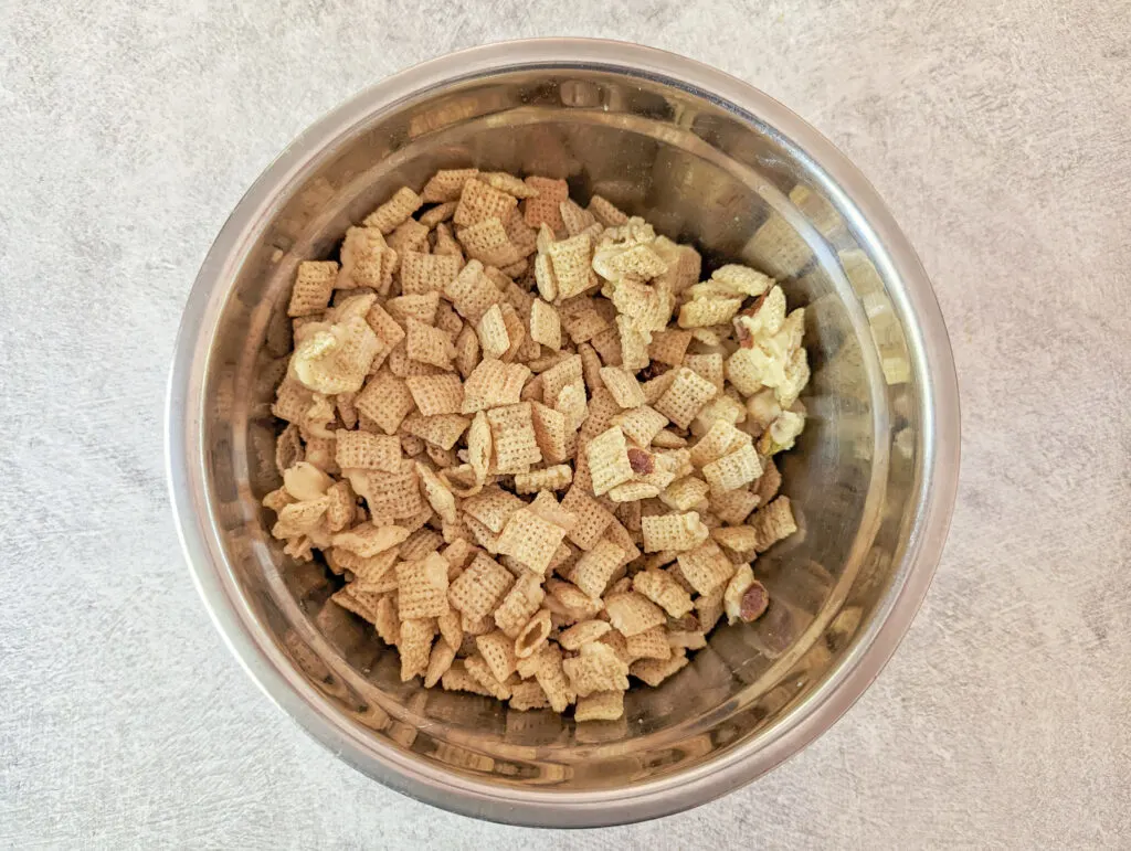 Butter and melted chocolate poured over the chex cereal in a mixing bowl.