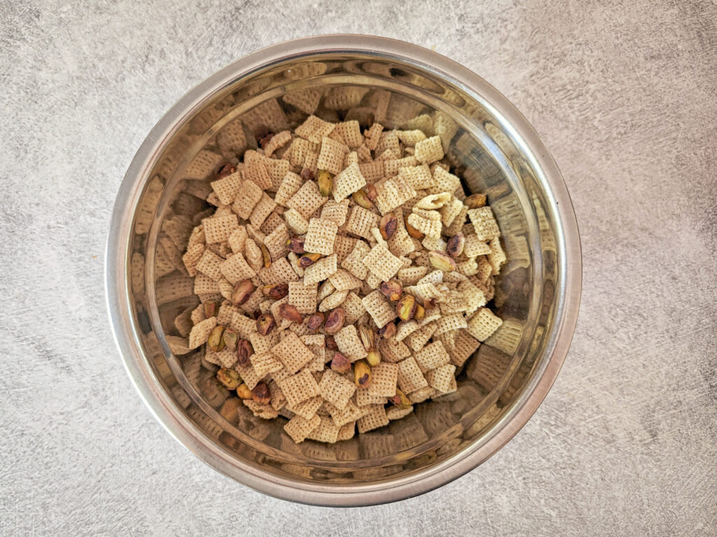 Chex cereal and pistachios in a mixing bowl.