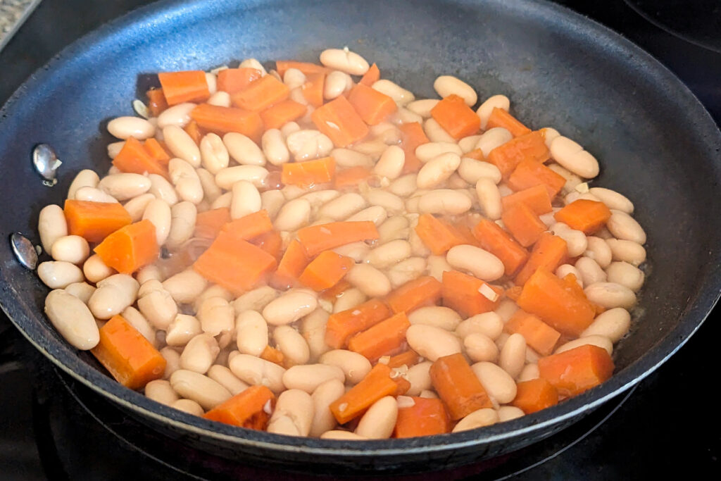 Beans added to the cooking carrots and garlic.