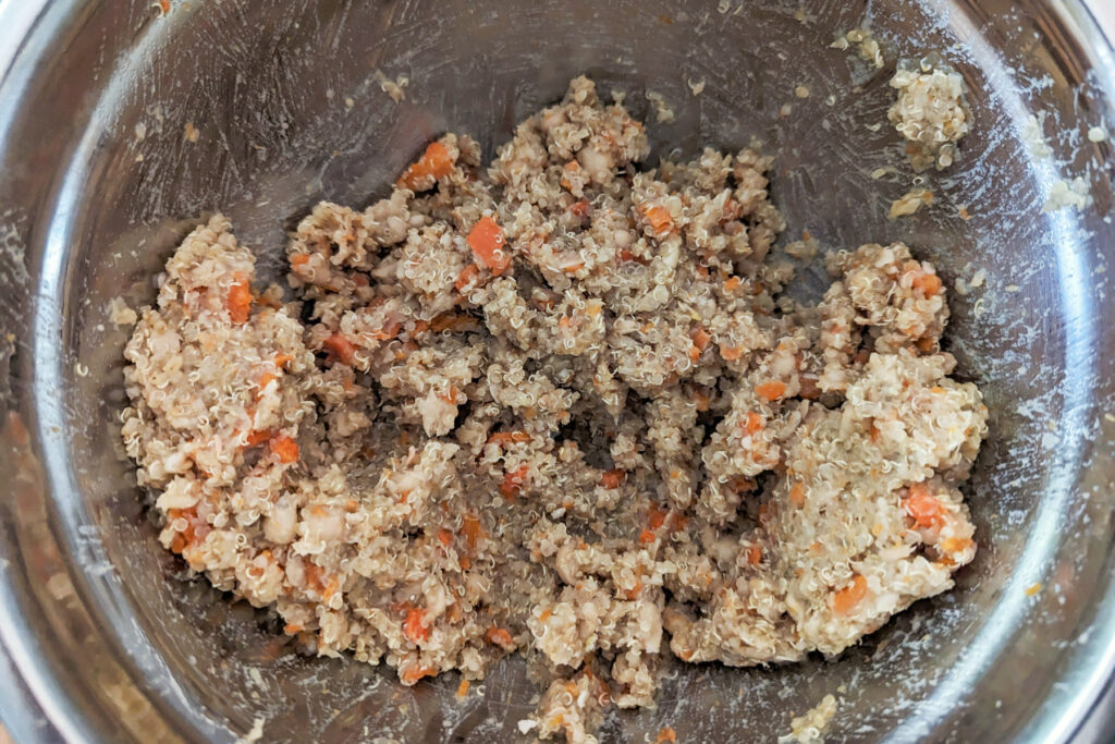 Quinoa, vegetables, and beans mashed in a mixing bowl.