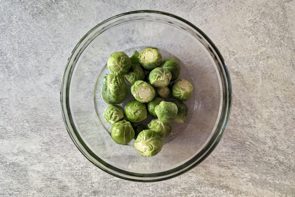 Brussels sprouts in a bowl with water.