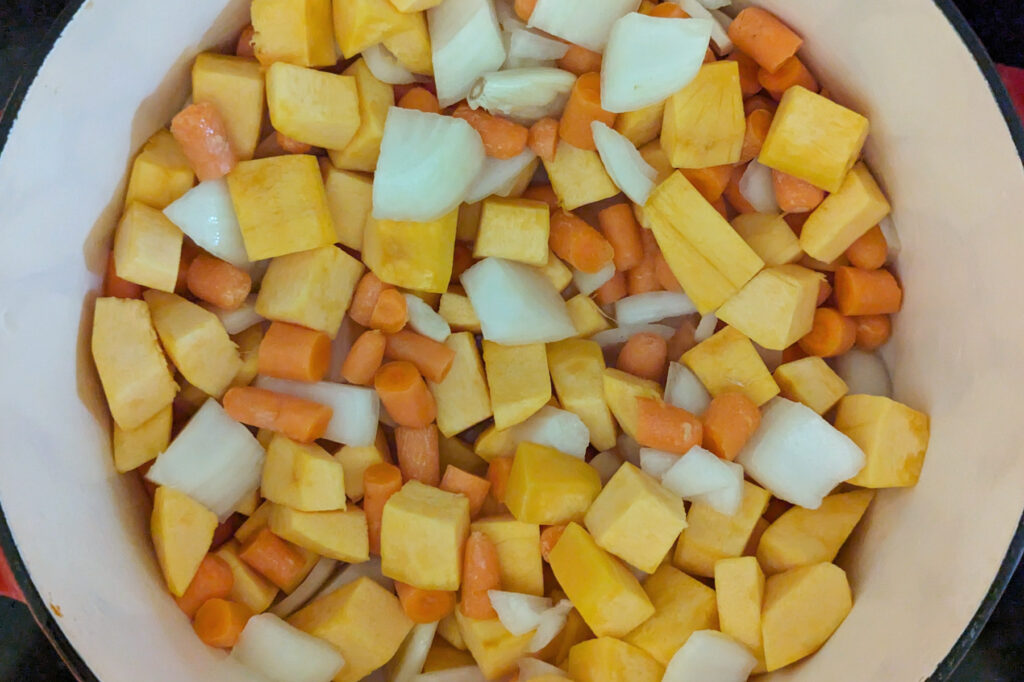 Carrot, pumpkin, onions and garlic sautéing in a dutch oven.