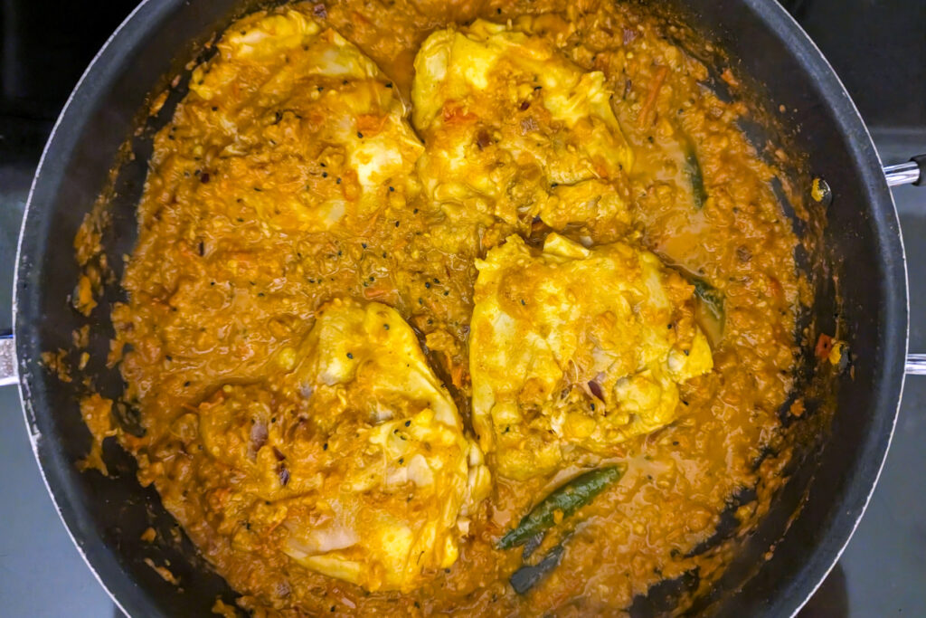 Chicken thighs nestled into the masala.