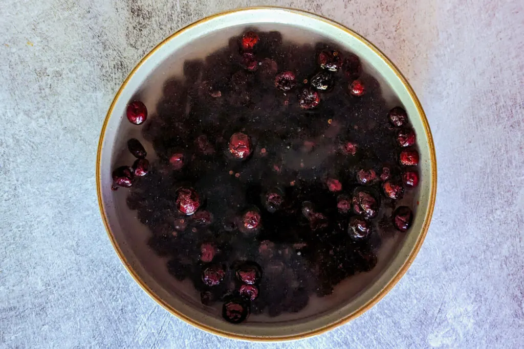 Dried cranberries rehydrating in a bowl.
