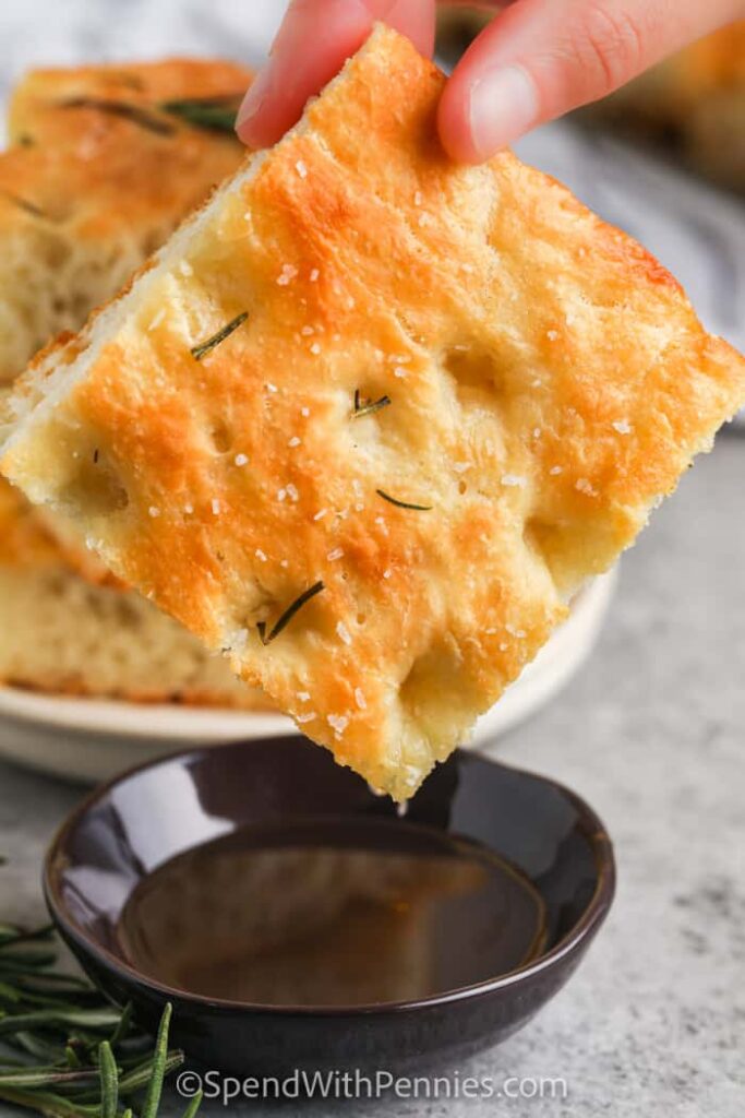 A cut piece of foccocia bread in olive oil dip.