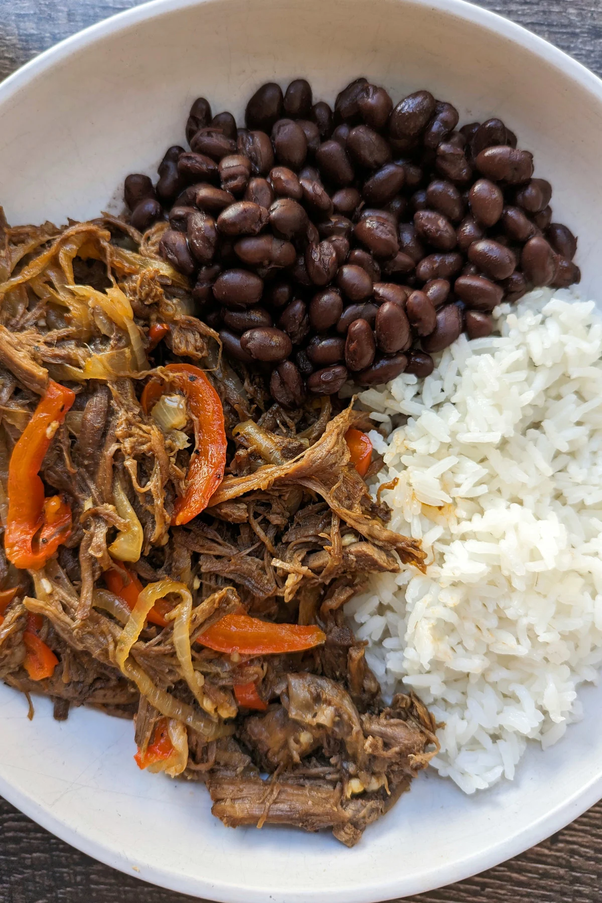 Carne Mechada on a plate with rice and beans.