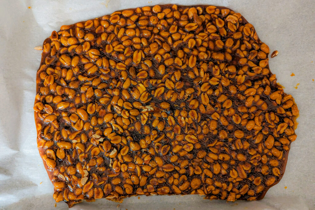 Peanut brittle mixture spread onto a pan with parchment paper. 