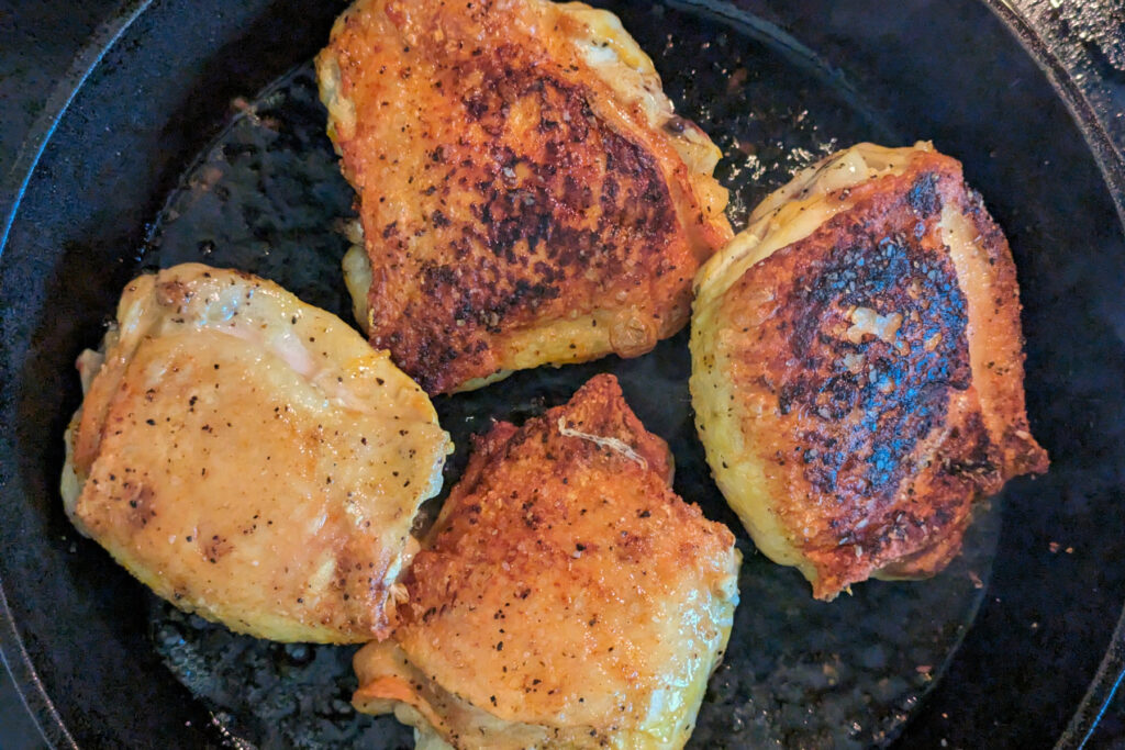 Chicken searing in a pan.