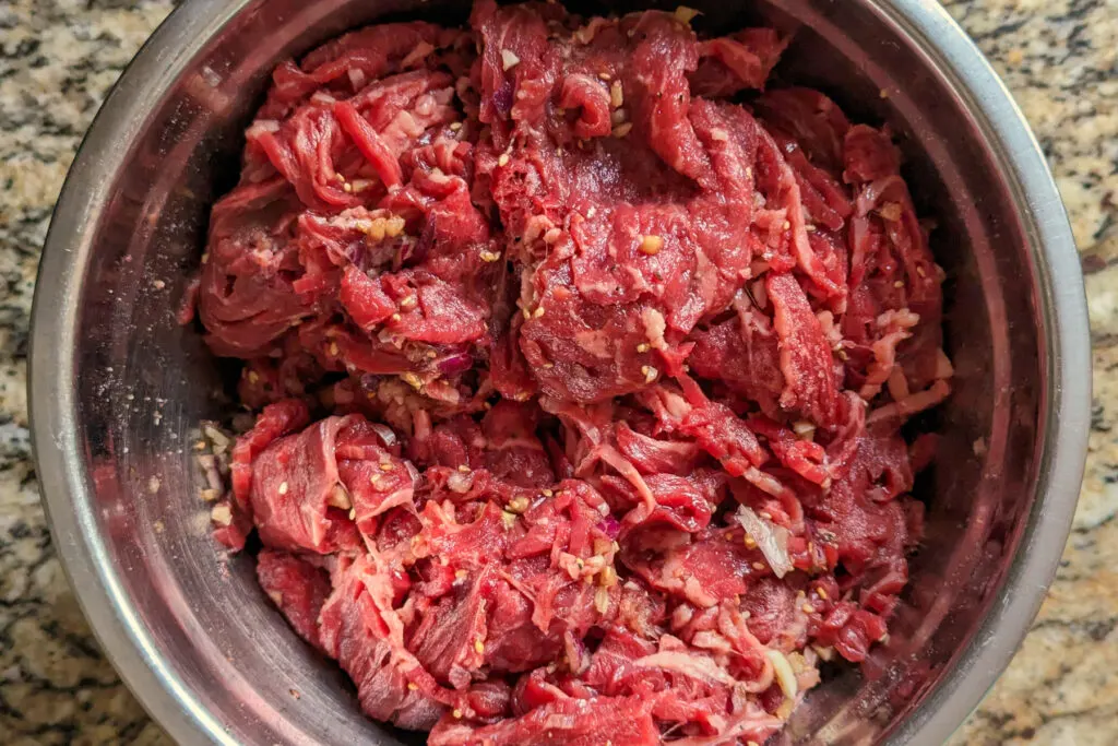 Sirloin steak marinating in a bowl.