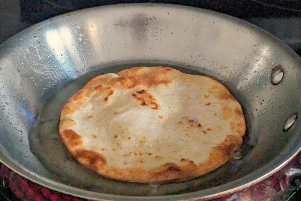 A corn tortilla frying in a pan.