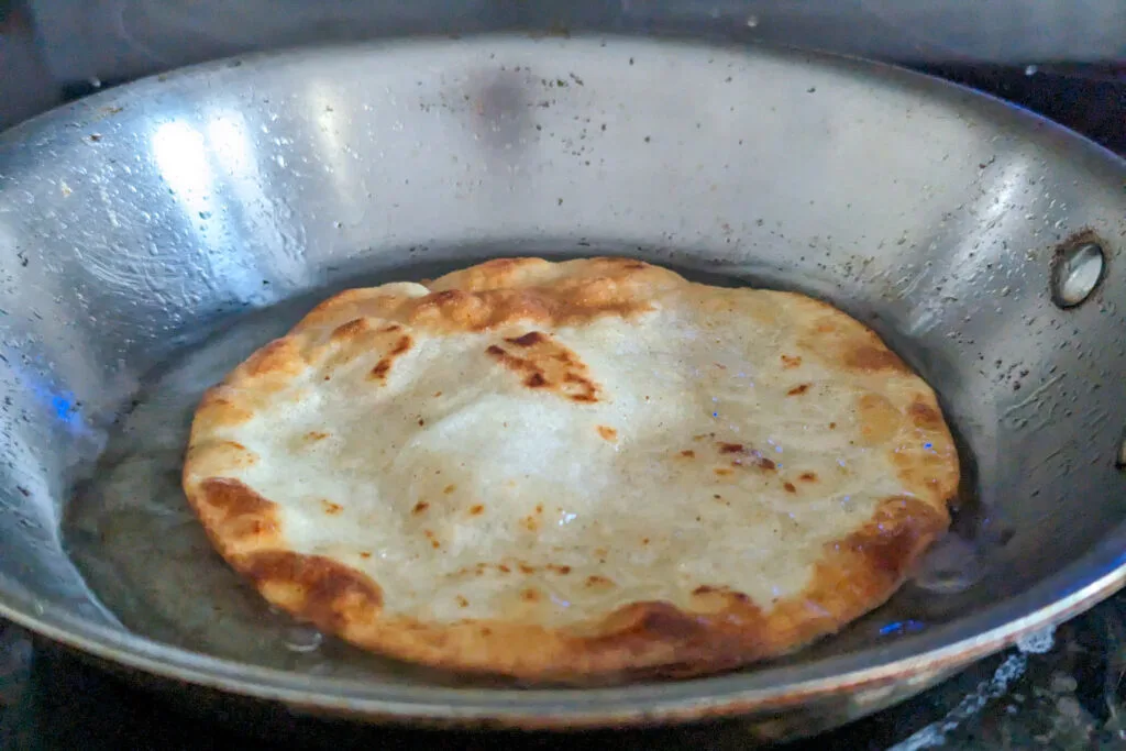 Corn tortillas frying in a pan.