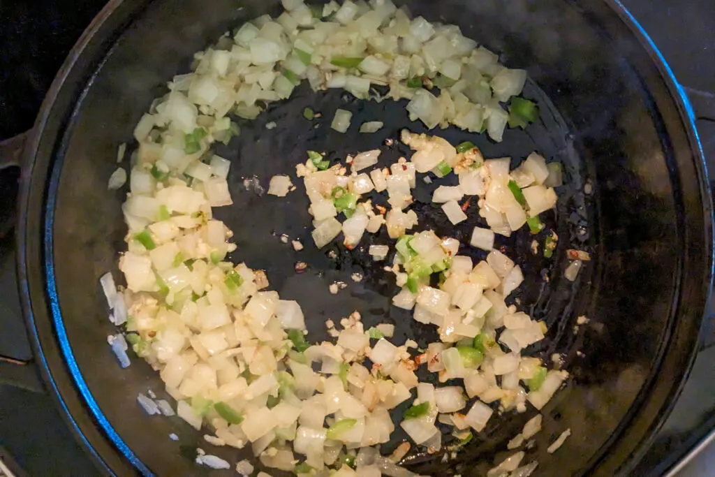 Onions and peppers sauteing in a pan.