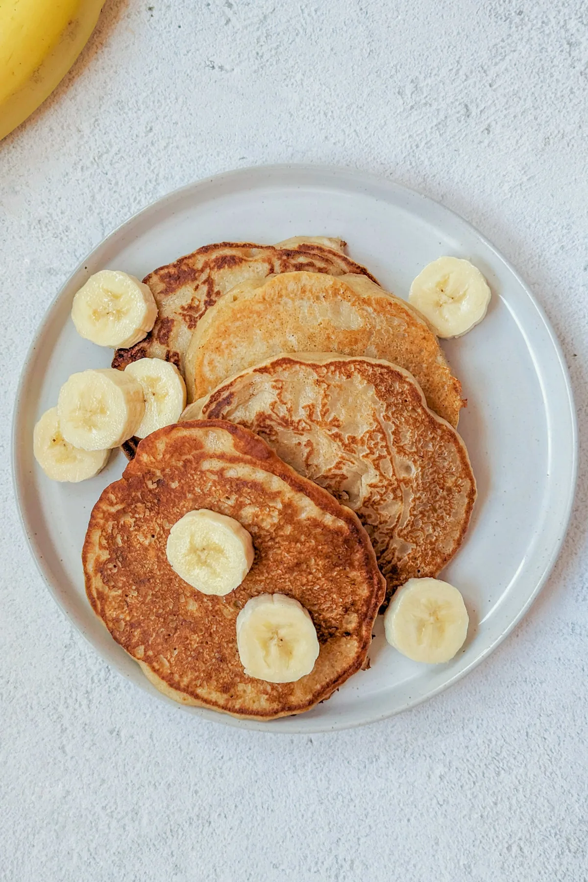 Sourdough banana pancakes with syrup and banana slices.
