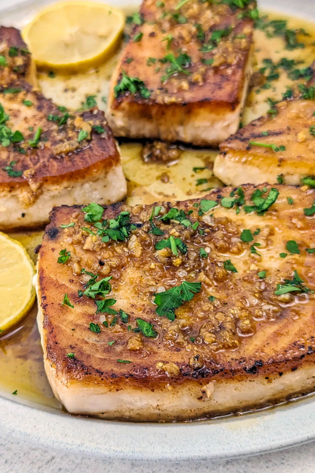 Fried swordfish on a plate with parsley.