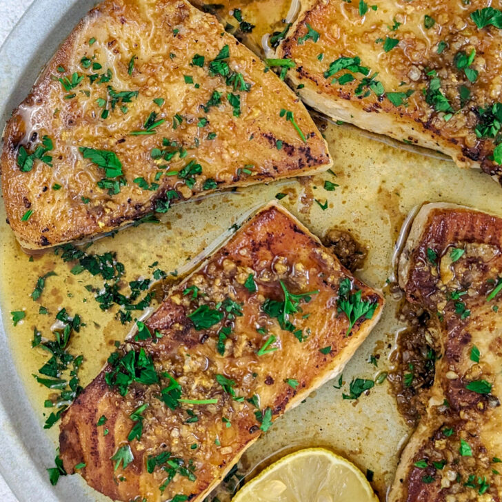 Fried swordfish on a plate with parsley.