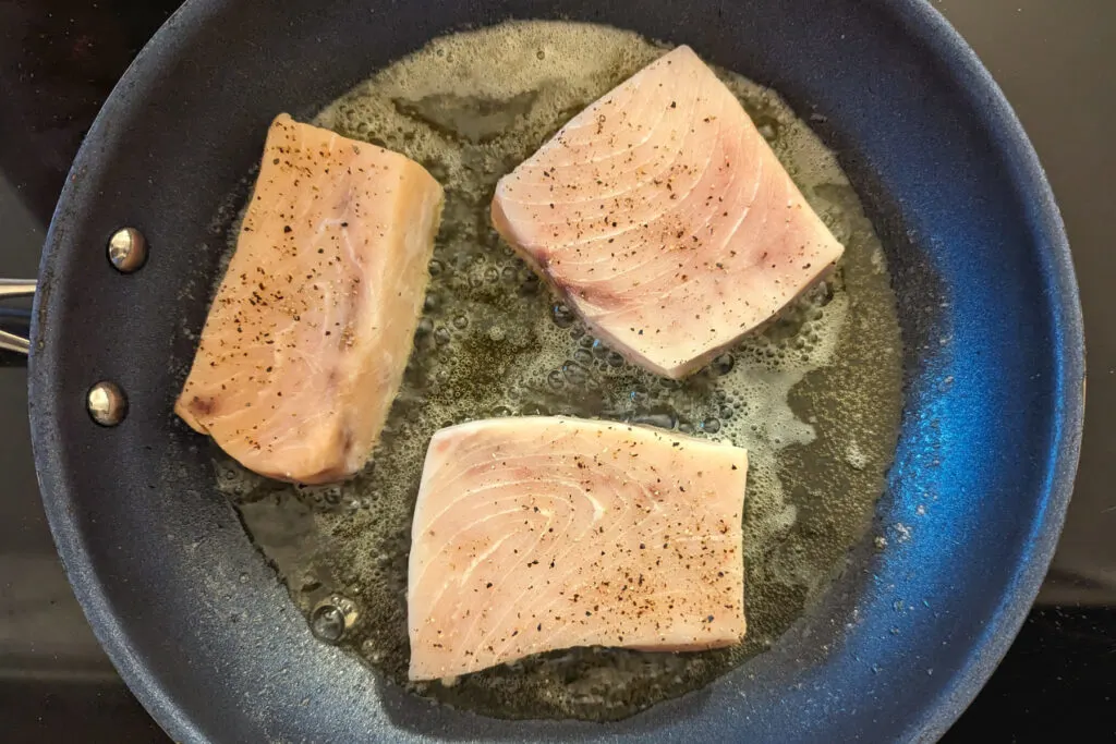 Swordfish searing in a pan.