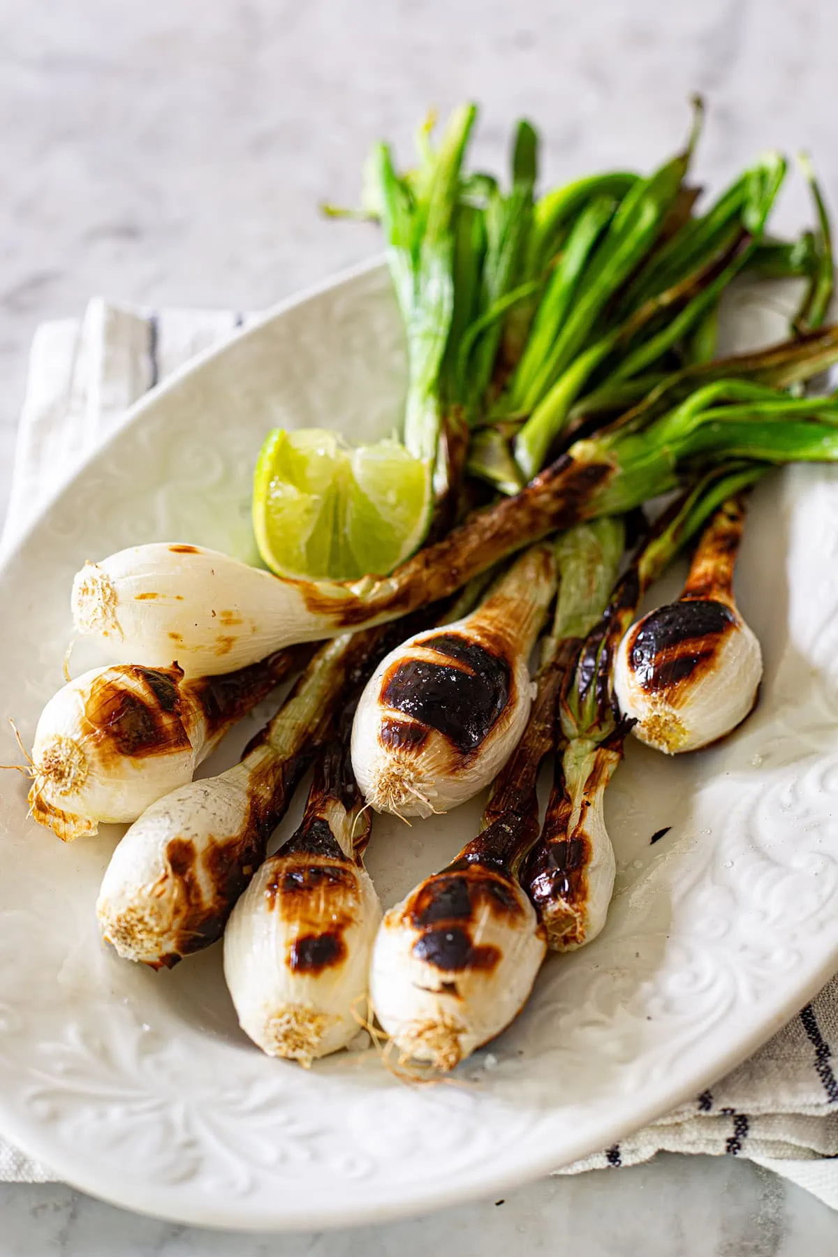 Grilled green onions on a plate.