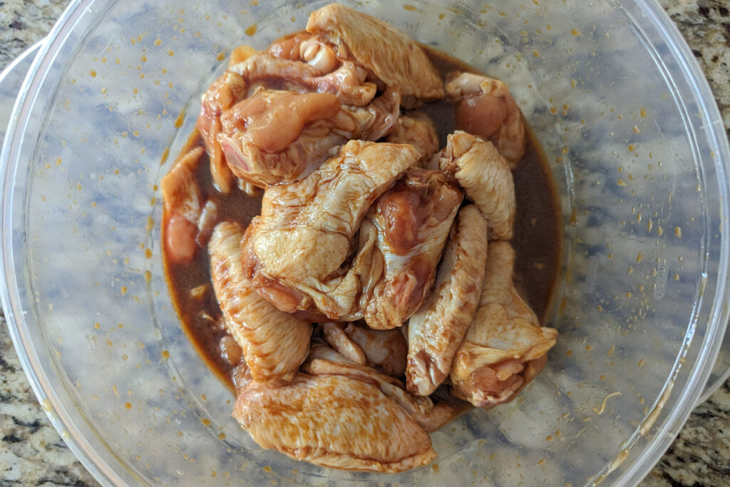 Chicken wings in a bowl of marinade.