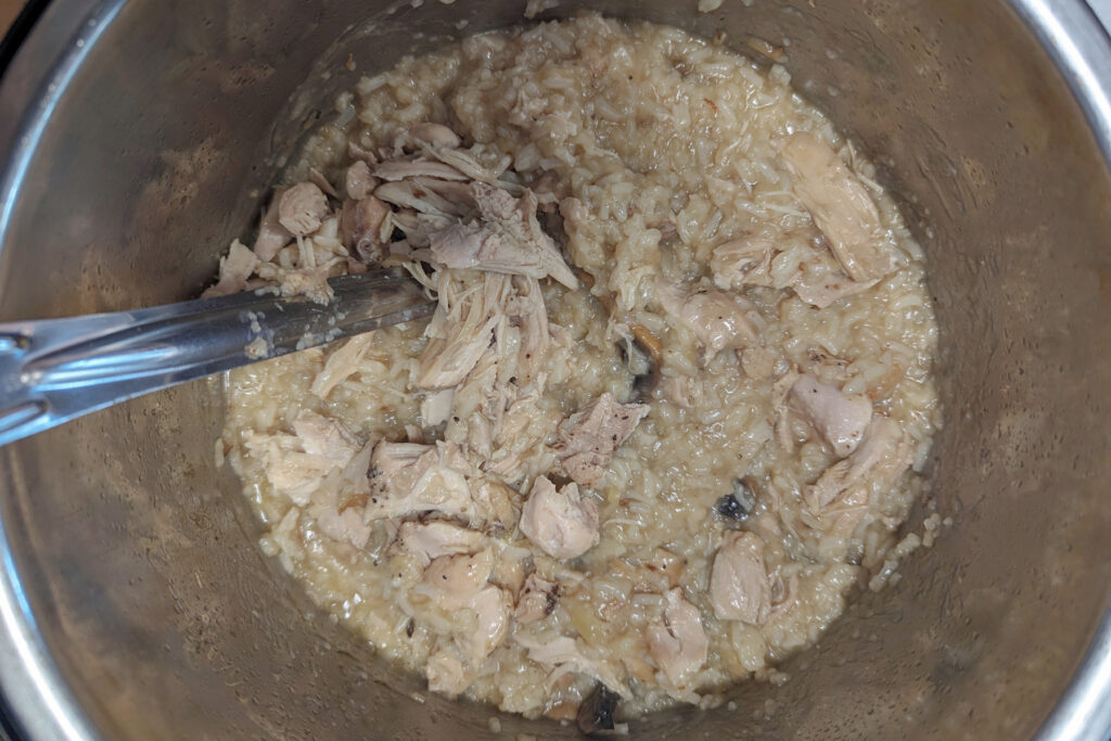 Cooked arroz caldo with the chicken returned to the Instant Pot.