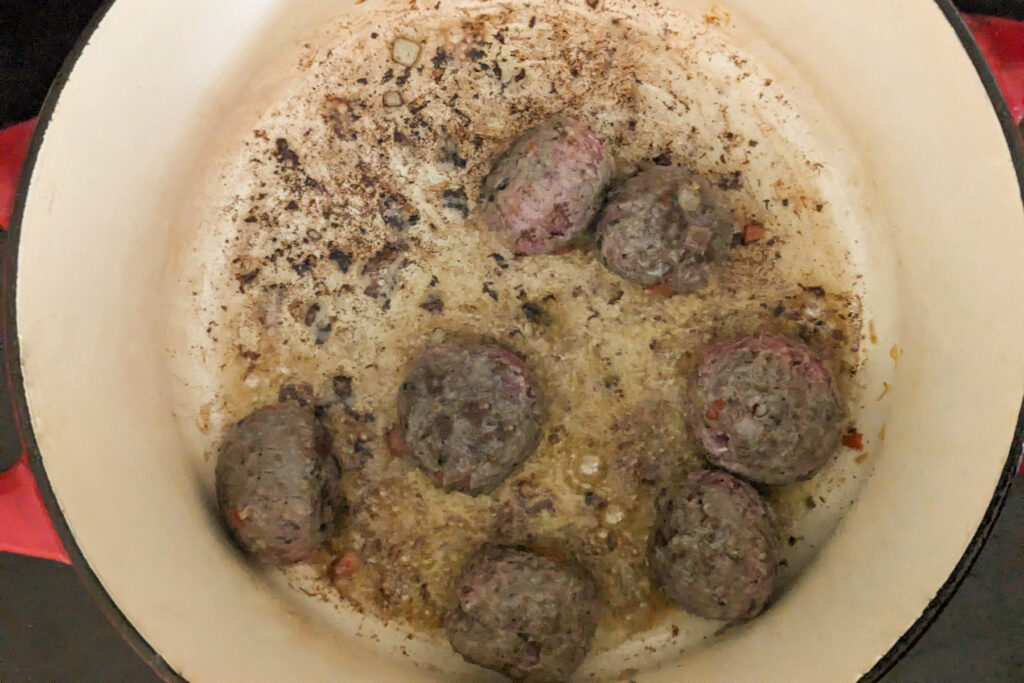 Meatballs searing in a pan.