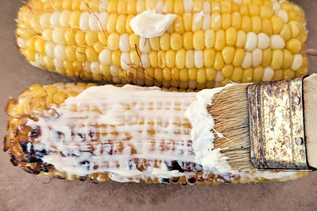 Crema brushed onto an ear of corn.