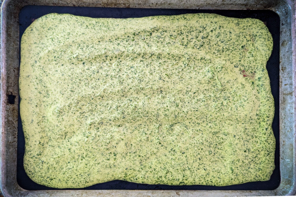 Spinach mixture spread onto a baking sheet.