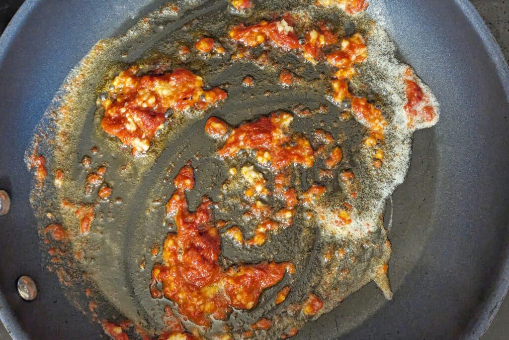 Tomato paste and garlic in a pan.