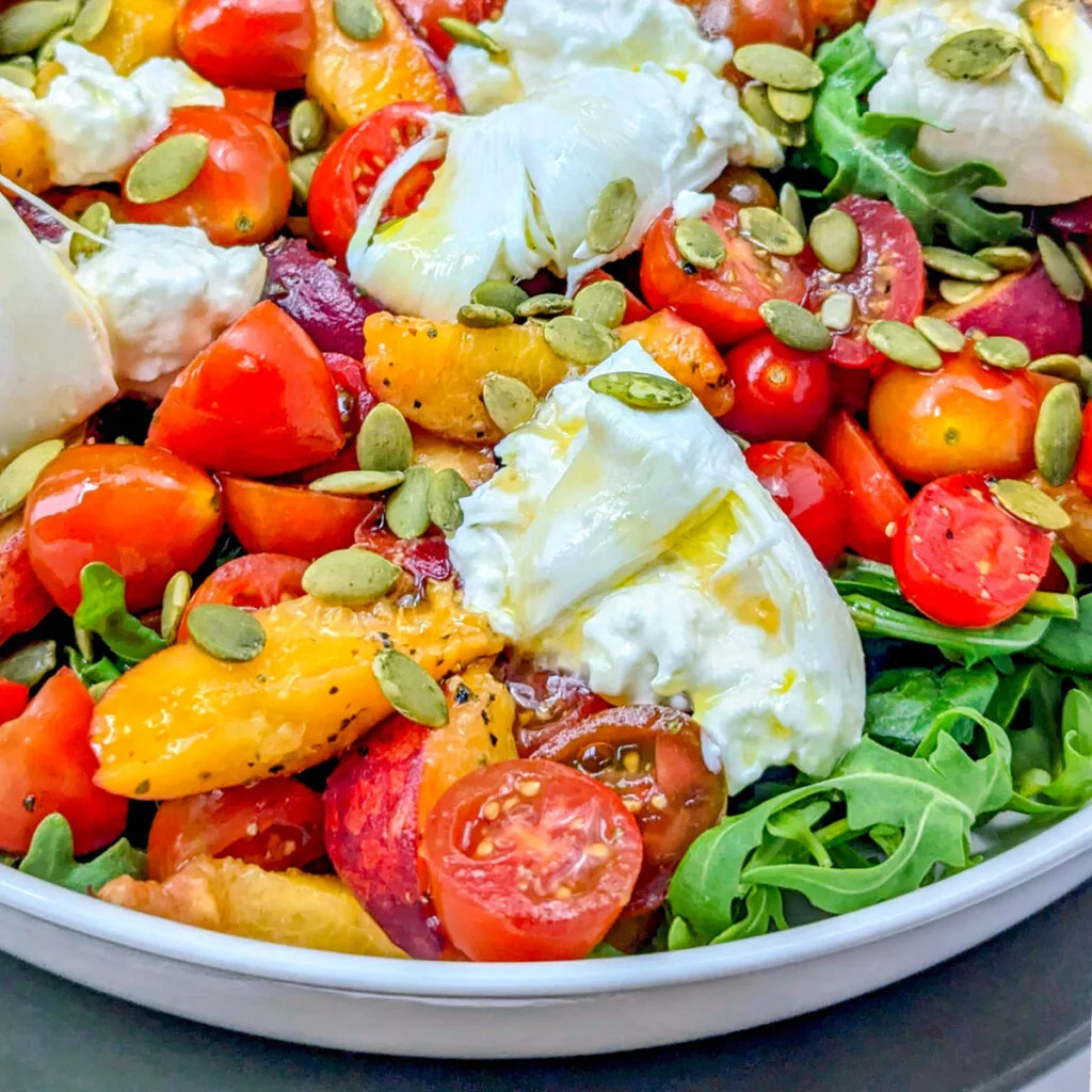 Burrata tomato peach salad in a serving bowl.