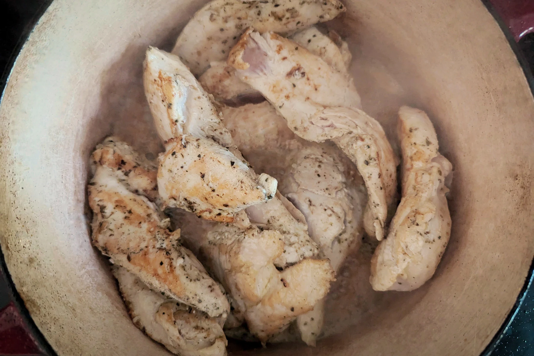 Chicken cooking in a Dutch oven.
